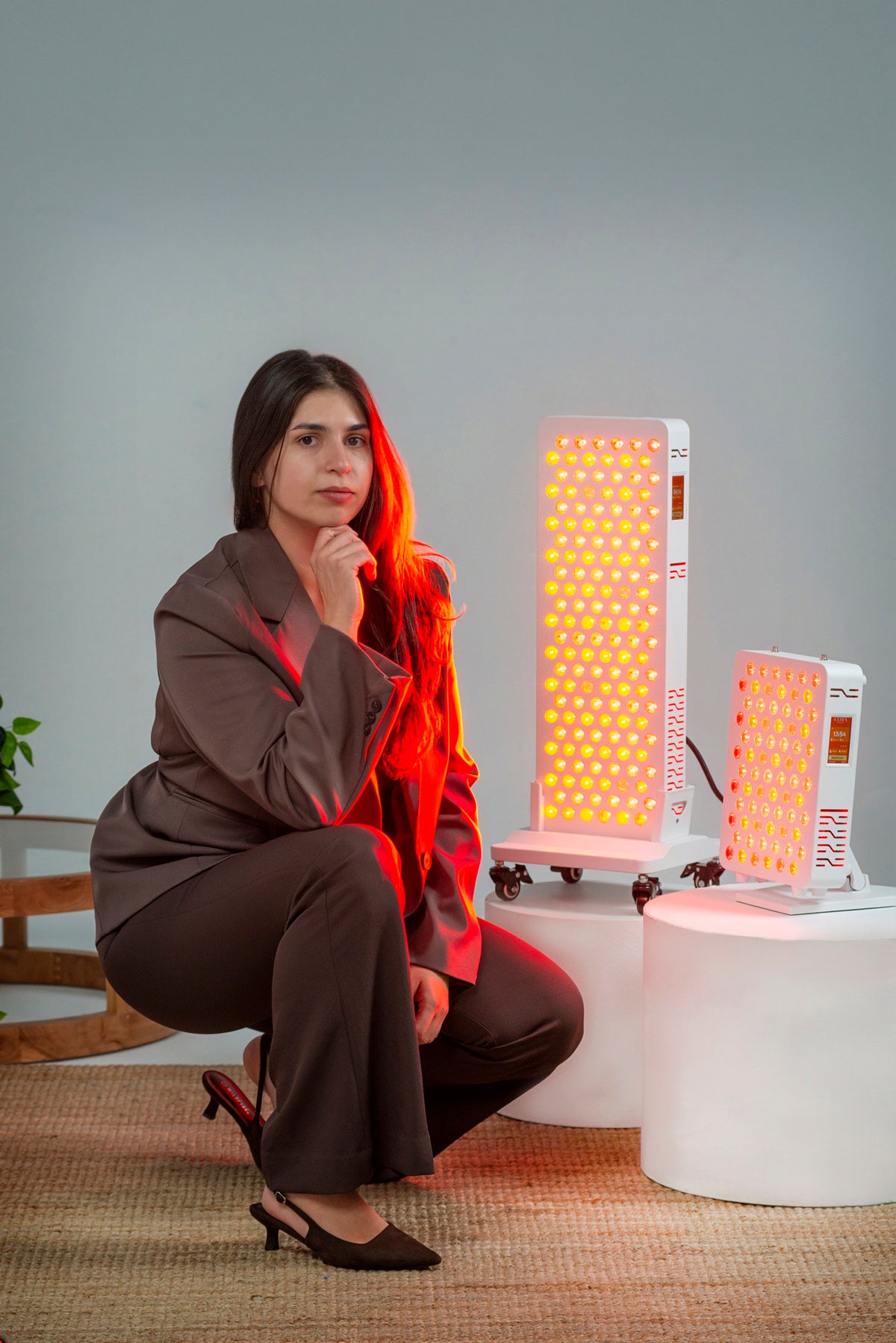 Woman seated beside the Ultra Pro 200 and Ultra Mini 100 red light panels